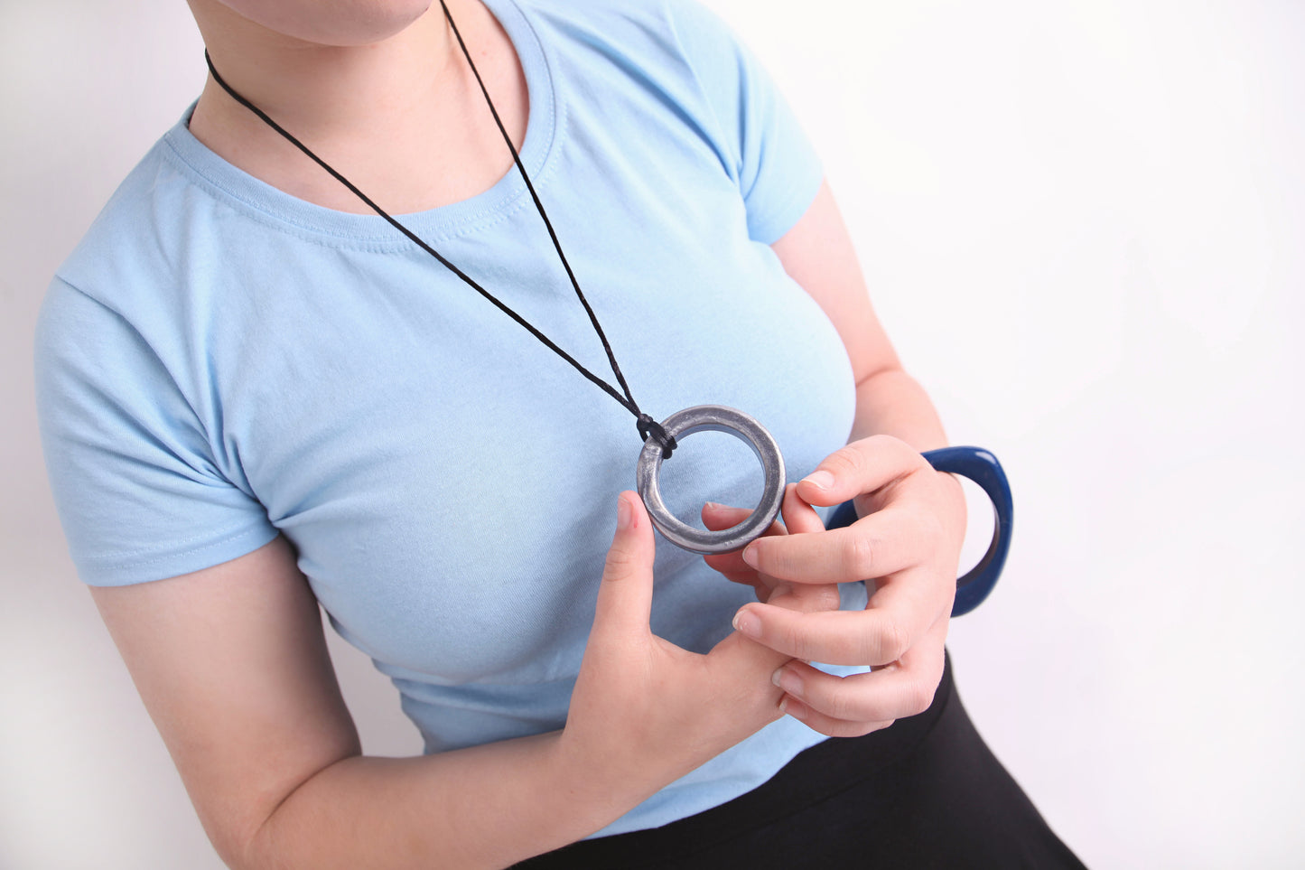 Person holding a silver ring realm  pendent necklace 