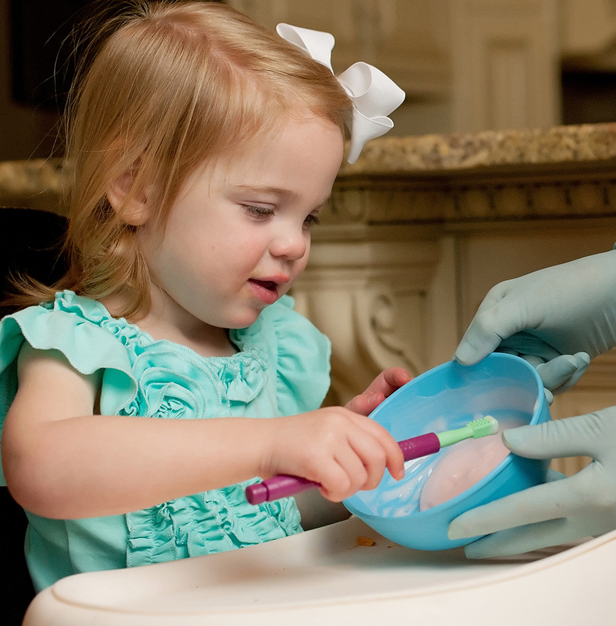 Child using the Mini Tip on the Z-Vibe as a dipper spoon in a bowl soft food